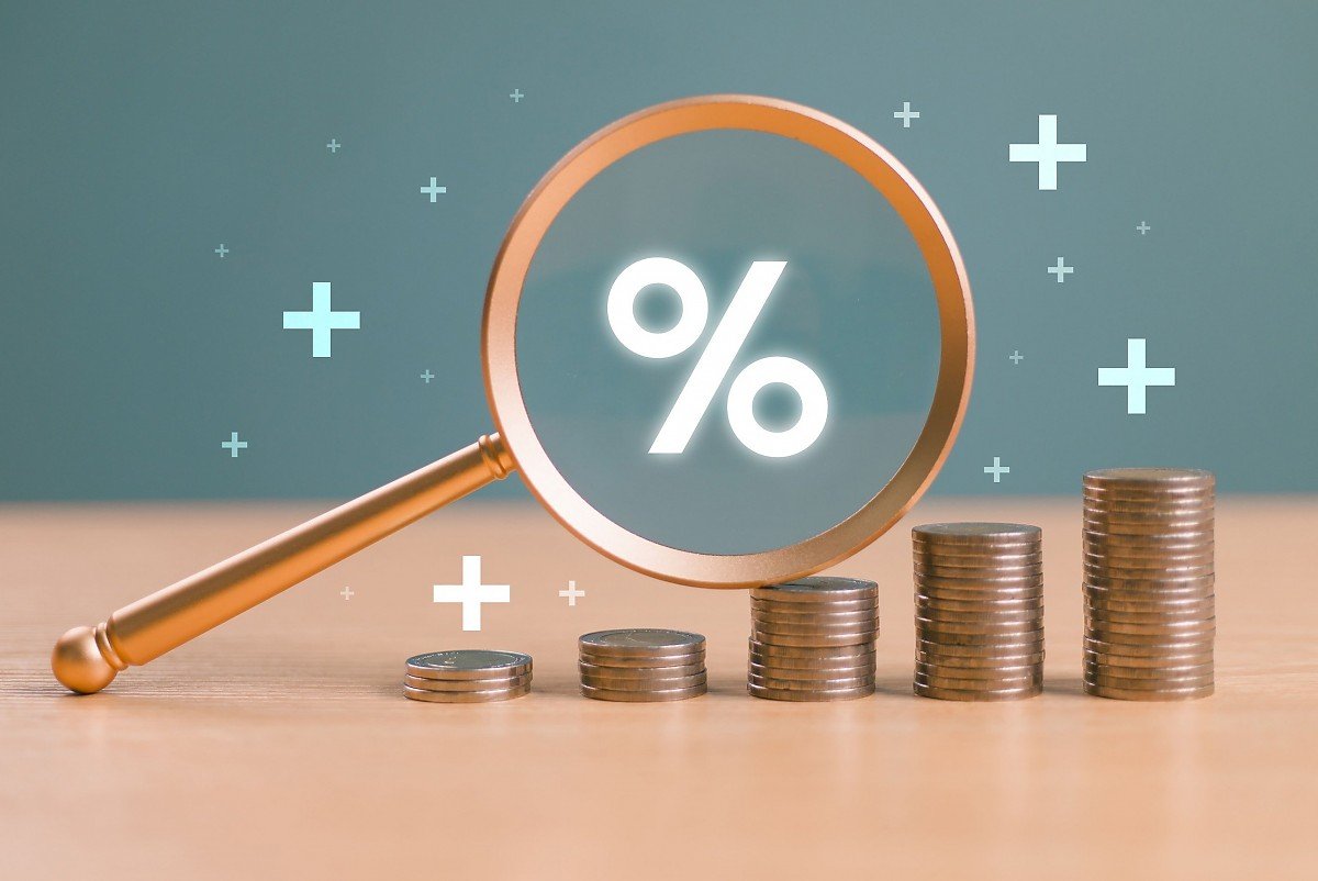 Lupe mit Prozentzeichen �ber M�nzstapeln