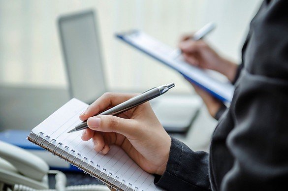 Frau macht auf einem Klemmbrett Notizen