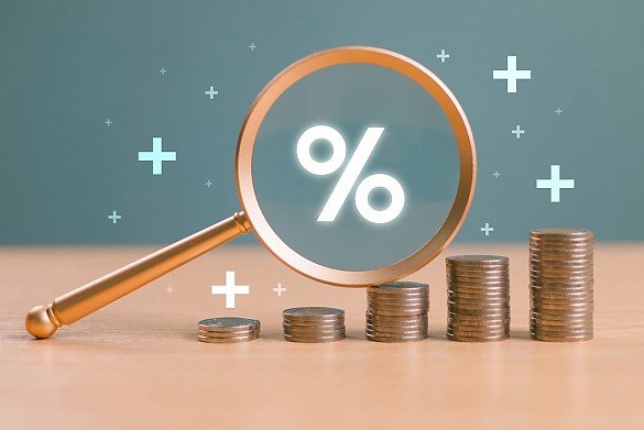 Lupe mit Prozentzeichen �ber M�nzstapeln